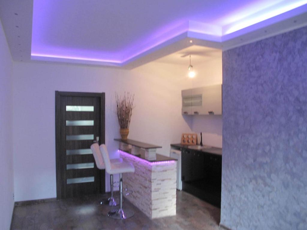 uma cozinha com iluminação roxa e uma mesa e cadeiras em Apartament Neon em Gdynia