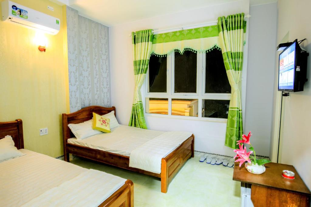 a bedroom with two beds and a tv and a window at Phuc Hau Hotel - Ly Son in Ly Son