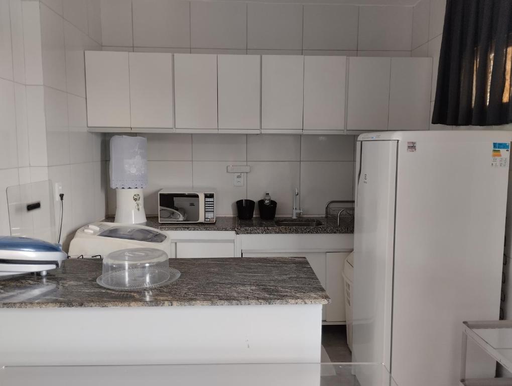 a kitchen with white cabinets and a white refrigerator at Apartamento Icaraí prox ao cumbuco in Caucaia