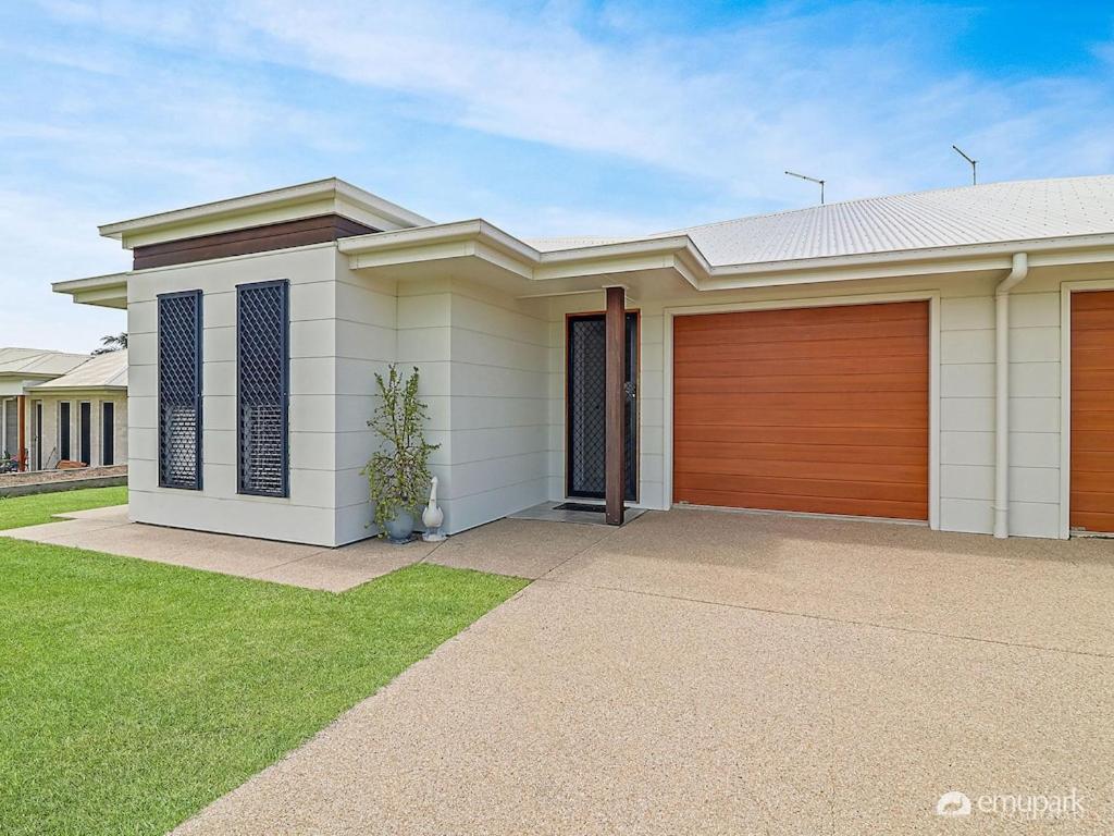 uma casa branca com uma garagem castanha em BEACH WALK ON HILL em Emu Park