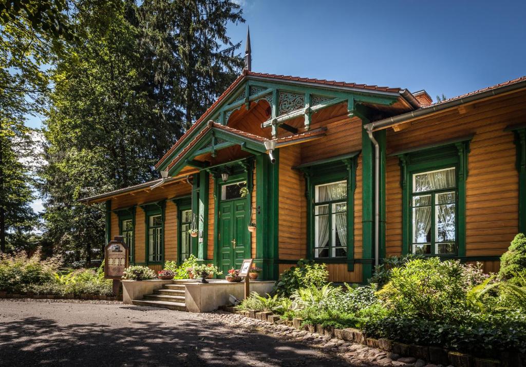 a green and wooden house with a tree at Apartamenty Carskie in Białowieża