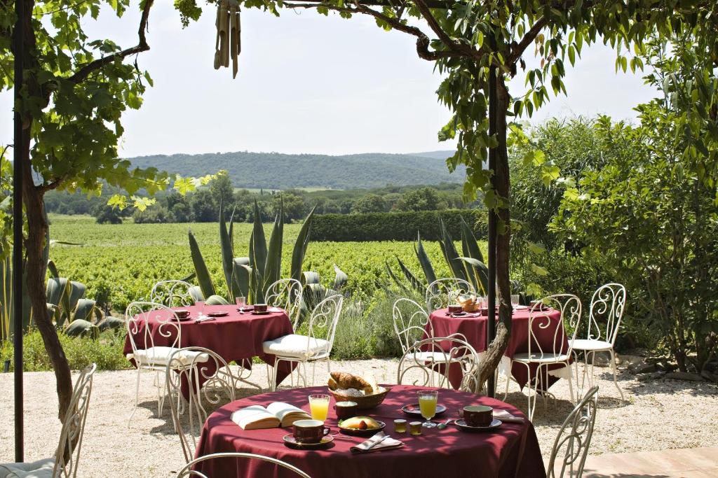 a table with red table cloths and chairs in front of a field at Saint-Vincent in Saint-Tropez