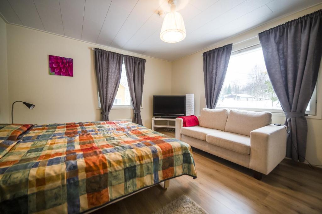 1 dormitorio con cama, sofá y TV en Hotel Aakenus Holiday Home Kymppi, en Rovaniemi