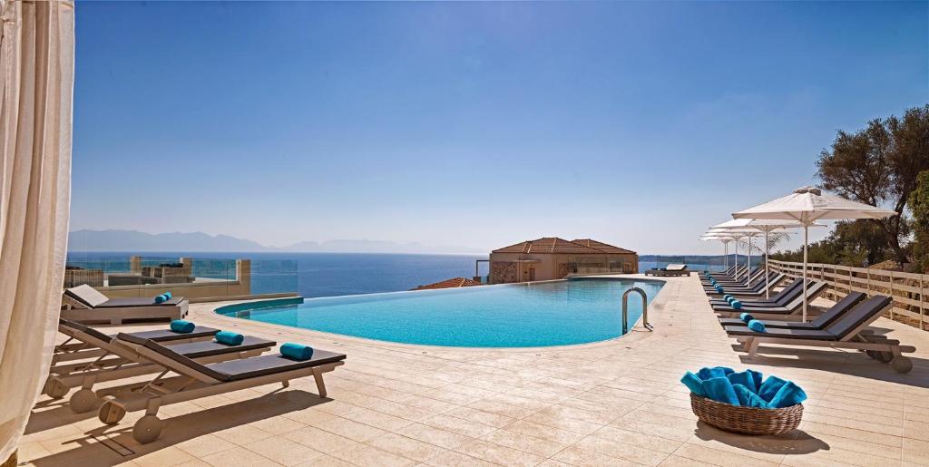 a swimming pool with lounge chairs and the ocean at Camvillia Resort Messinia in Vounaria