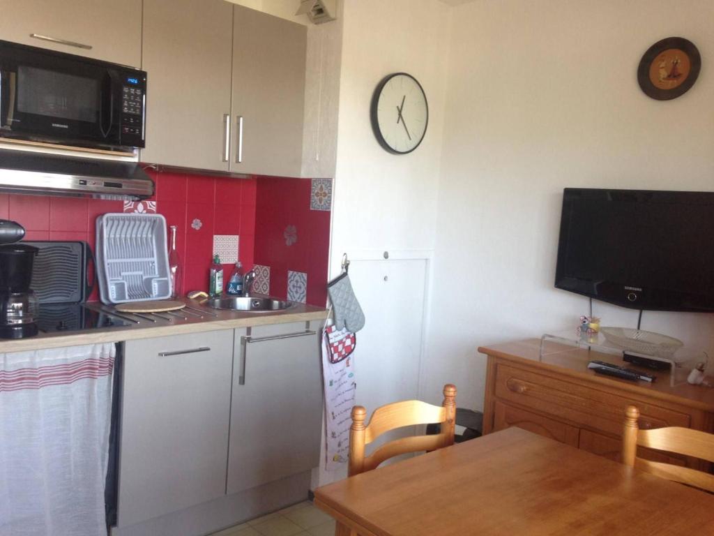 une cuisine avec une table et une horloge au mur dans l'établissement Appartement Charmant avec Piscine, Tennis et Parking à Capbreton, Proche Océan et Port de Plaisance - FR-1-239-880, à Capbreton
