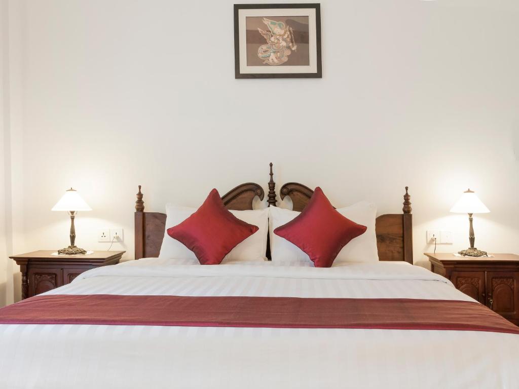a bedroom with a large white bed with red pillows at Chateau d'Angkor La Residence in Siem Reap