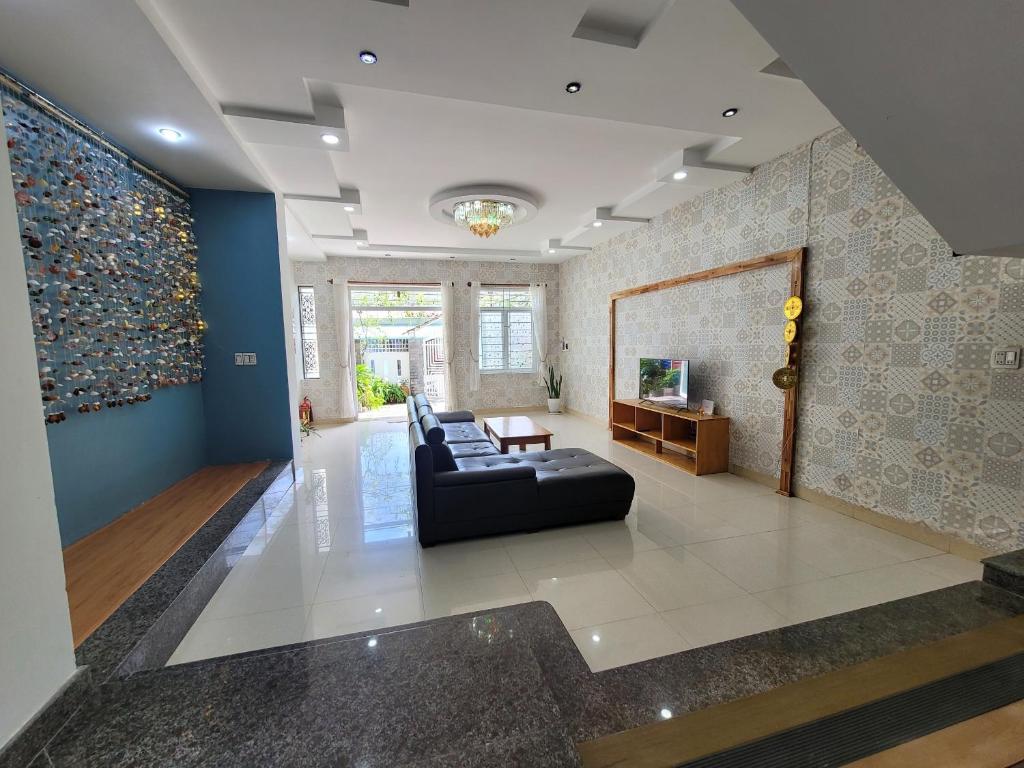 - un salon avec un canapé noir et un mur dans l'établissement Q House- Green Villa Quy Nhơn, à Quy Nhơn