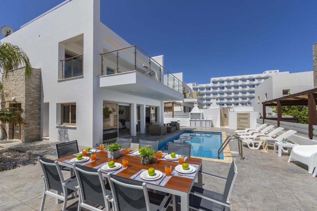 a patio with a table and chairs and a swimming pool at Protaras Sunrise Beach Villa 2 in Protaras
