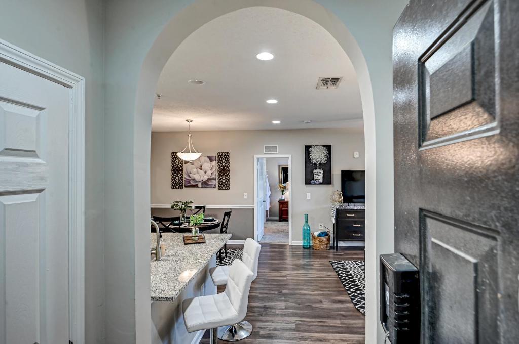 a hallway leading to a living room with white furniture at Westside Retreat with Private Balcony Nr DWTN Jax in Jacksonville
