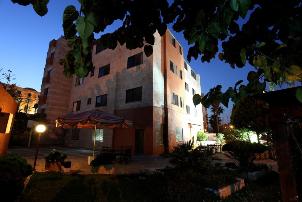 un edificio con una sombrilla delante de él en Barakat Hotel Apartments, en Amán