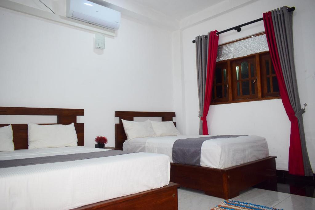 sypialnia z 2 łóżkami i oknem z czerwonymi zasłonami w obiekcie Eleven11 Resort w mieście Anuradhapura