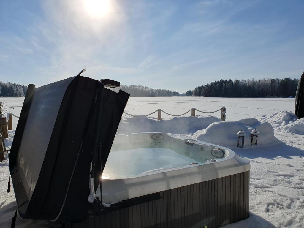 a jacuzzi tub in a snow covered field at Stunning log cabin 45m2 on the shore of Kallavesi. in Kuopio