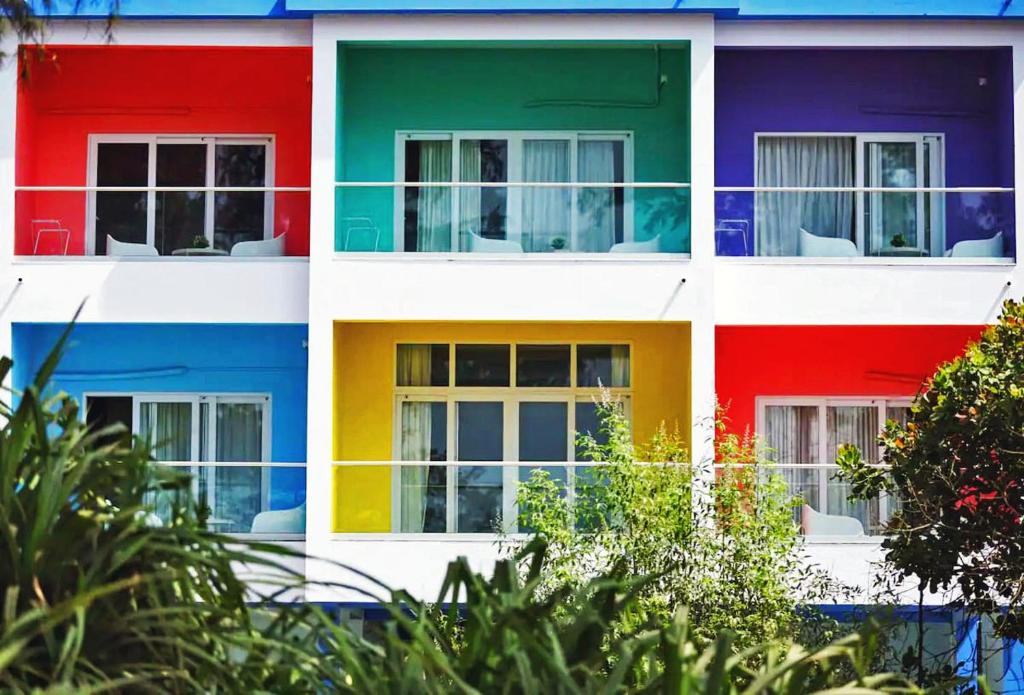 un edificio multicolor con sillas en las ventanas en STAYMAKER White Sand Beach Resort en Honāvar