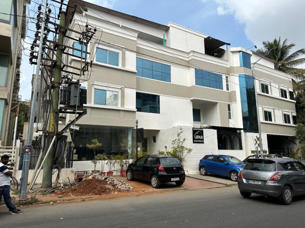 dwa samochody zaparkowane przed budynkiem w obiekcie Upar Hotels Indiranagar w mieście Bengaluru