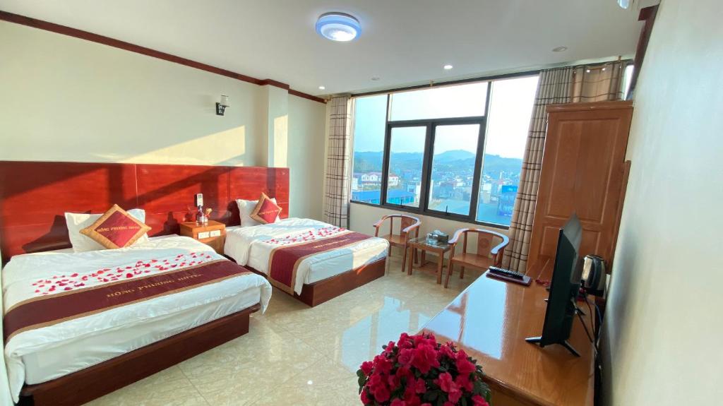 a hotel room with two beds and a flat screen tv at HỒNG PHƯƠNG HOTEL in Cao Bằng