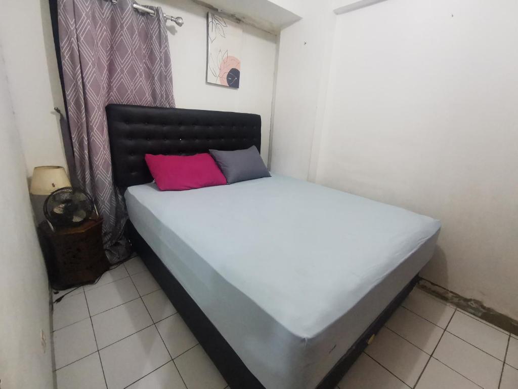 - un lit blanc avec un oreiller rouge dans l'établissement Cibubur Village Wina Property, à Cibubur