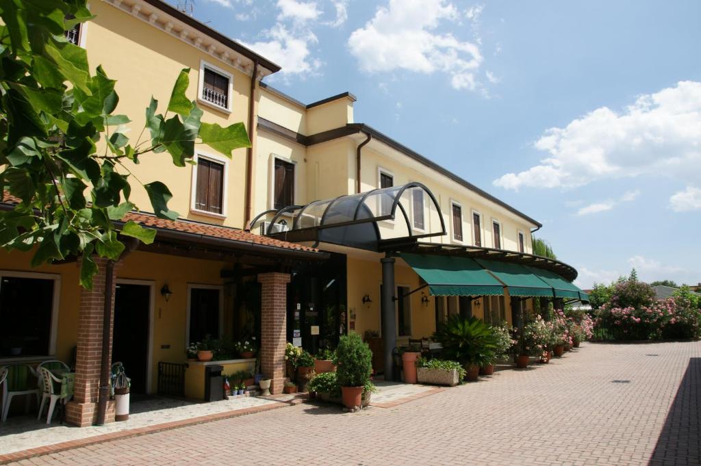 a large yellow building with a patio and plants at Locanda Grego in Bolzano Vicentino