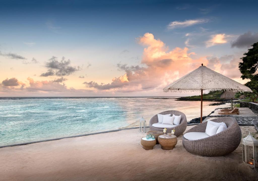 een strand met twee stoelen en een parasol en de oceaan bij La Maison d'Eté Hotel by NEWMARK in Poste Lafayette