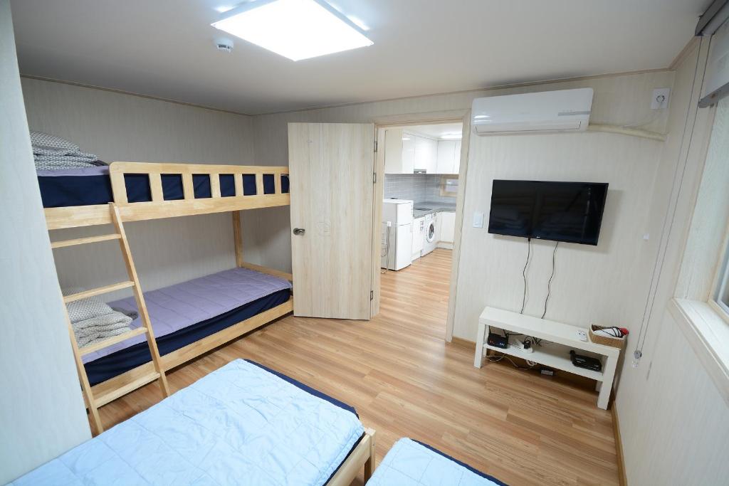 a small room with bunk beds and a flat screen tv at Sunnyhill Guesthouse Hongdae in Seoul