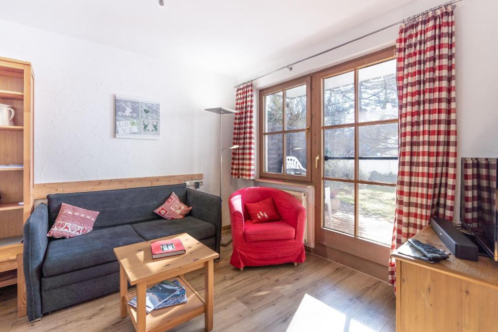 een woonkamer met een bank en een rode stoel bij Almlove in Bad Hindelang