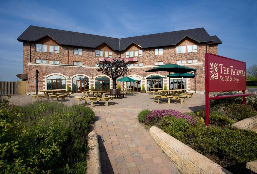 un gran edificio de ladrillo con mesas y sombrillas en The Fairway, en Barnsley