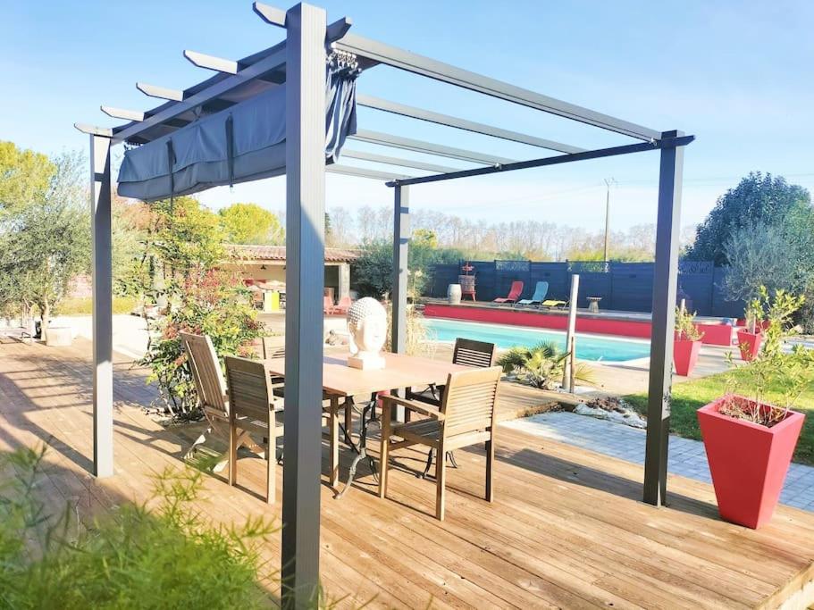 patio ze stołem i krzesłami pod niebieskim baldachimem w obiekcie Villa Moderne * Piscine privée 5x10 * Climatisation * Camargue w mieście Marsillargues