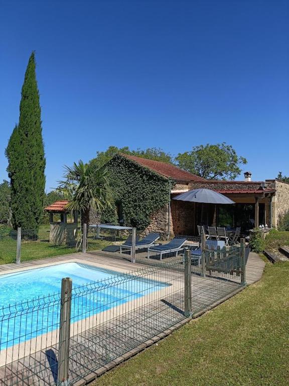 une maison dotée d'une piscine avec des chaises et un parasol dans l'établissement La Borie Blanche en Périgord Noir, à La Borie Blanche