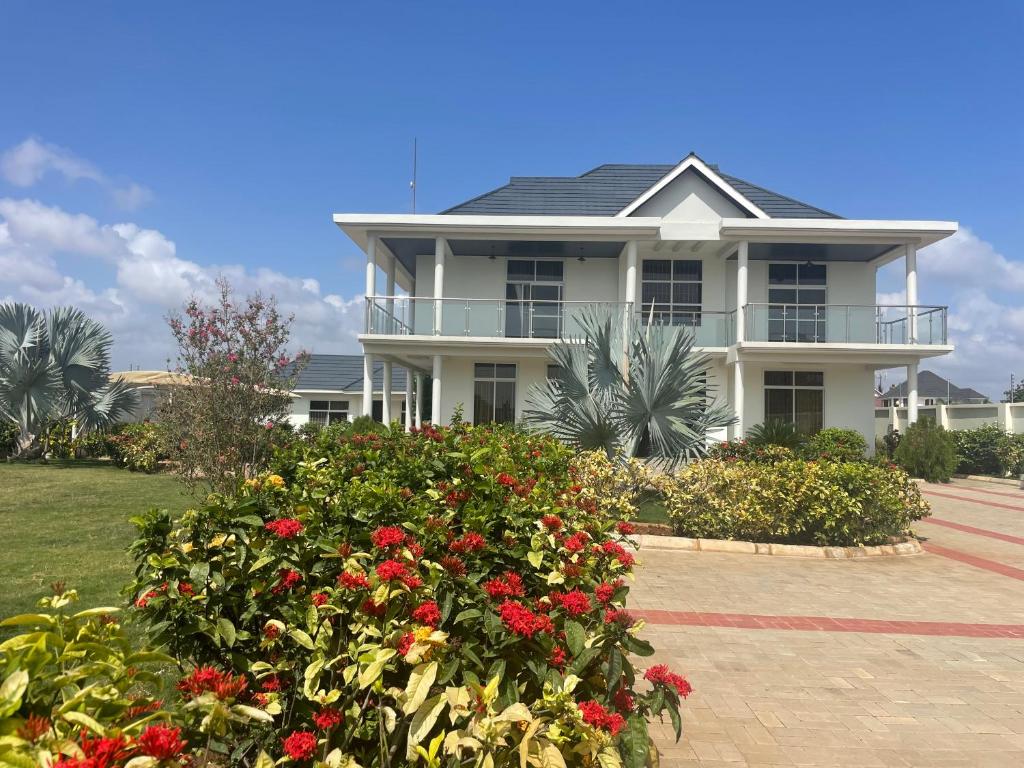 a large white house with flowers in front of it at Dar Villa in Dar es Salaam