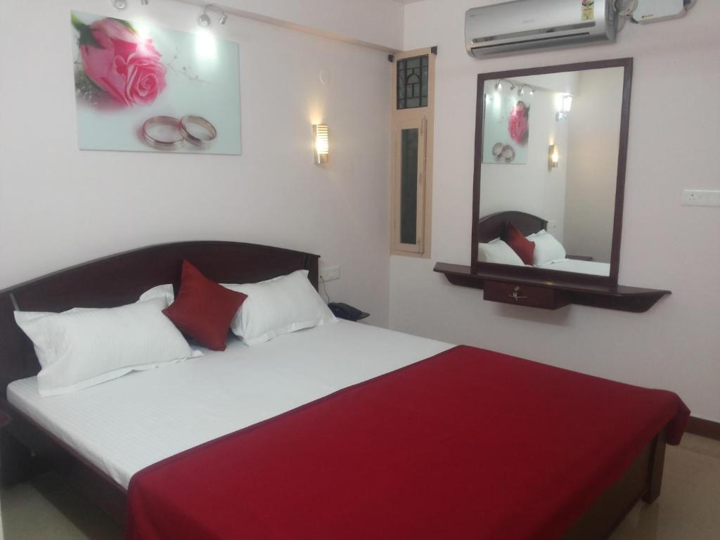 a bedroom with a bed with a red blanket and a mirror at Hotel Nambi in Madurai