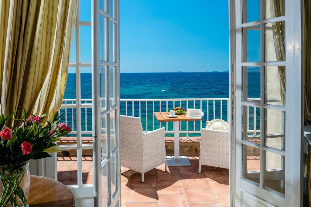 a room with a view of the ocean from a balcony at Hotel Le Maquis in Porticcio