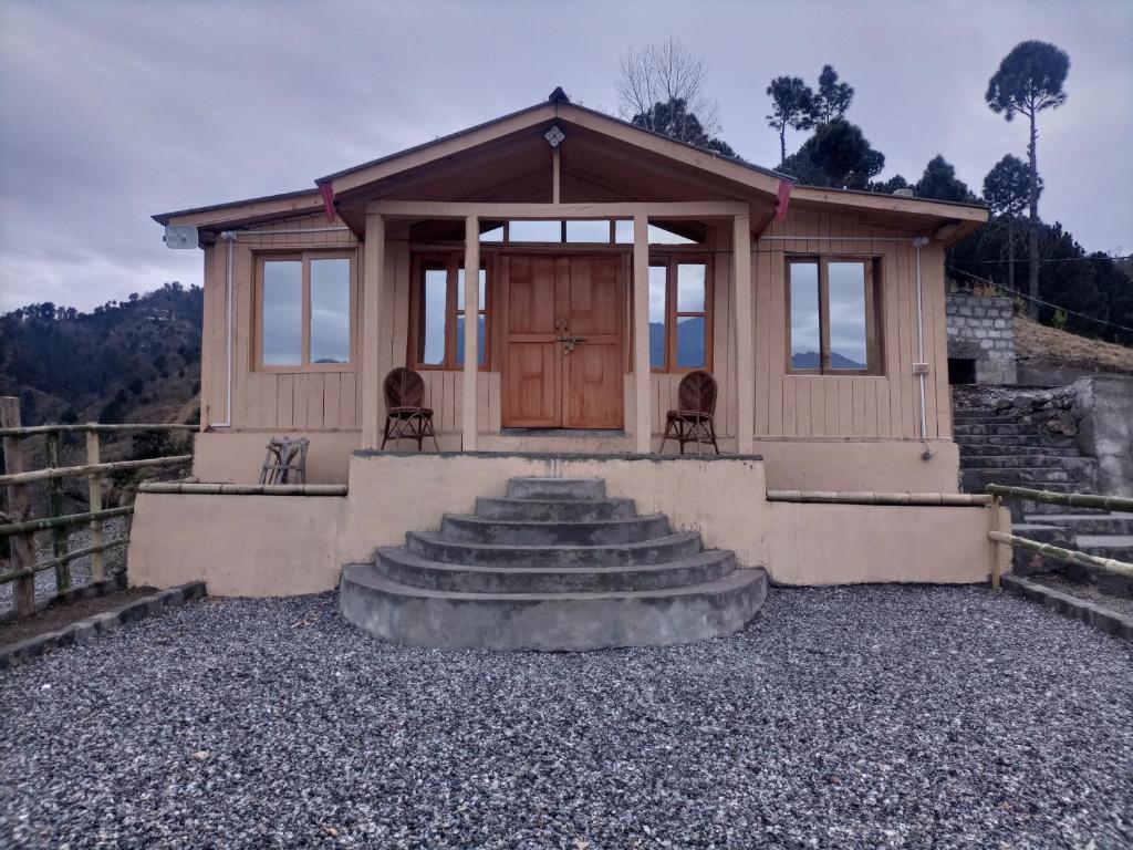 ein kleines Haus mit einer Veranda und einer Treppe davor in der Unterkunft Kashmir Eagle Heights Cottage & Restaurant by LMC in Muzaffarabad