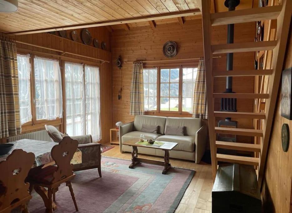 a living room with a bed and a couch and windows at Chalet Kuckuk in Habkern