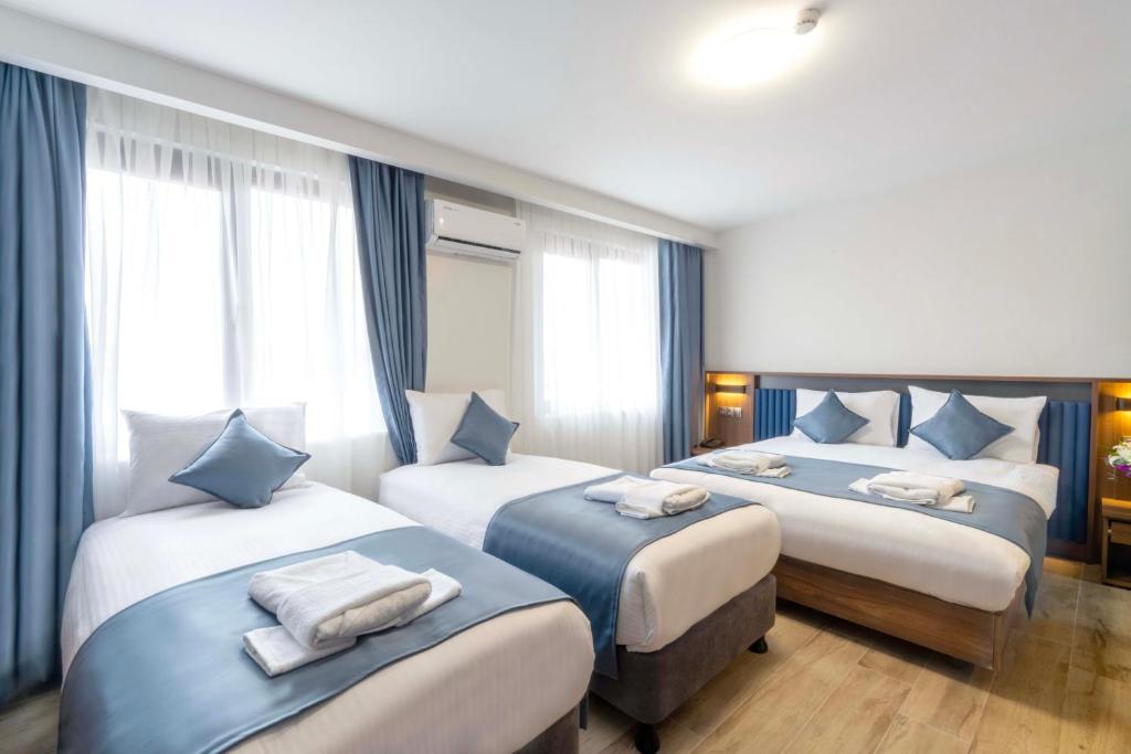 a hotel room with three beds with blue and white pillows at THE BOSFOR HOTEL in Istanbul