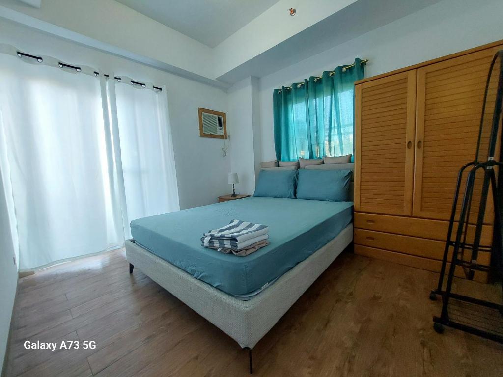 a bedroom with a bed with blue sheets and a wooden cabinet at Ania Summer Rooms in Mactan