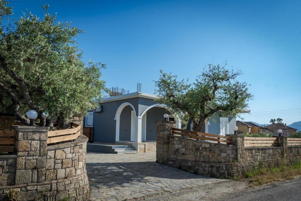 a house with a stone retaining wall and trees at Serotonin in Zakynthos Town