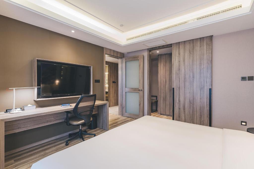 a room with a bed and a desk with a television at Atour Hotel Chongqiang Jiangbei Airport in Chongqing