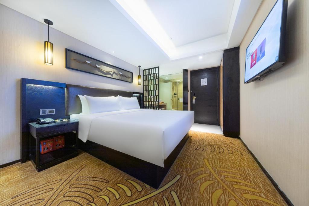 Atour X Hotel Shenzhen Luohu Dongmen Pedestrian Street في شنجن: غرفة نوم بسرير ابيض كبير وتلفزيون بشاشة مسطحة