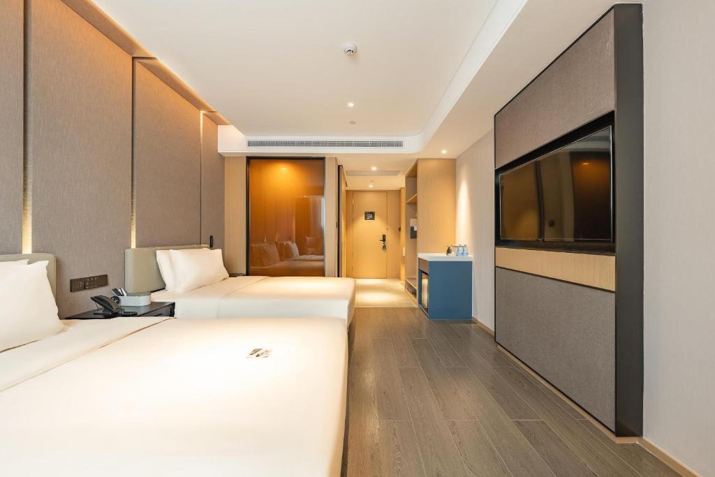 a hotel room with two beds and a flat screen tv at Atour Hotel Guangzhou Zhujiang New Town Wuyangtun in Guangzhou