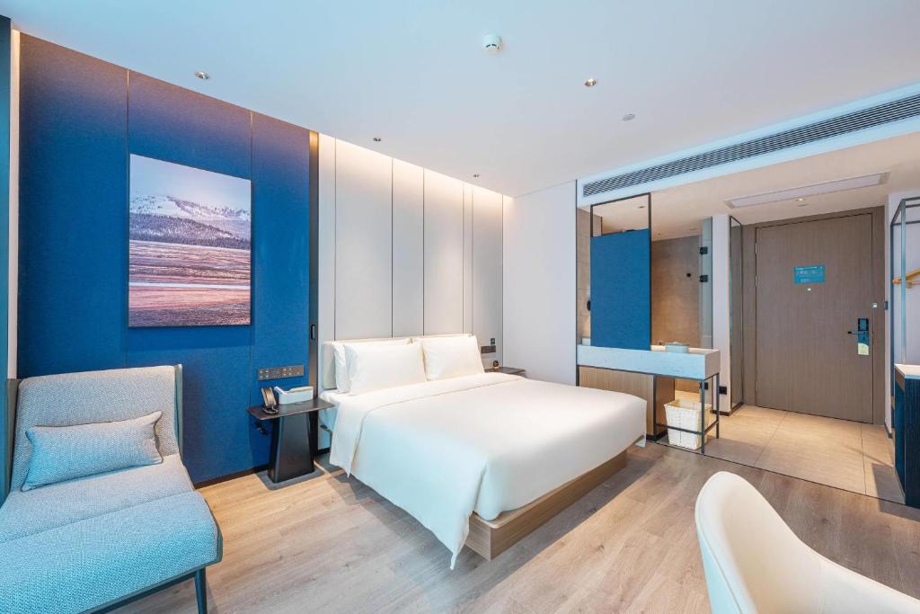 1 dormitorio con cama blanca y pared azul en Atour Hotel Shenzhen Baoan Vanke Star City, en Bao'an
