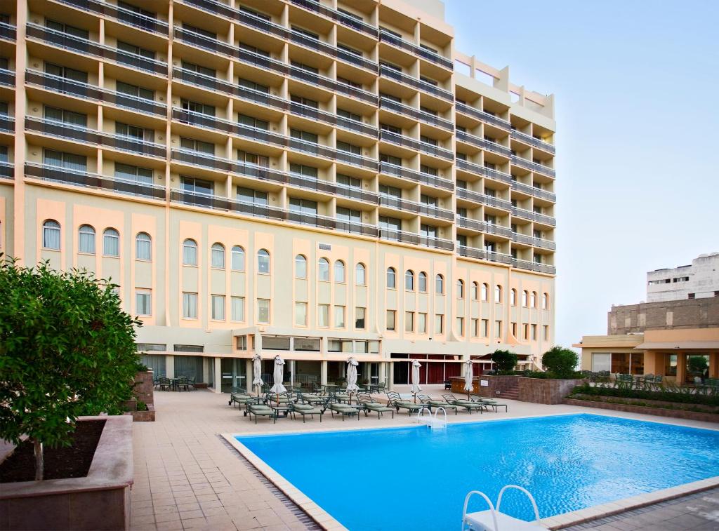 a large building with a large swimming pool in front of it at Treffen House Doha - next to Msheireb Metro Station and Souq Waqif in Doha