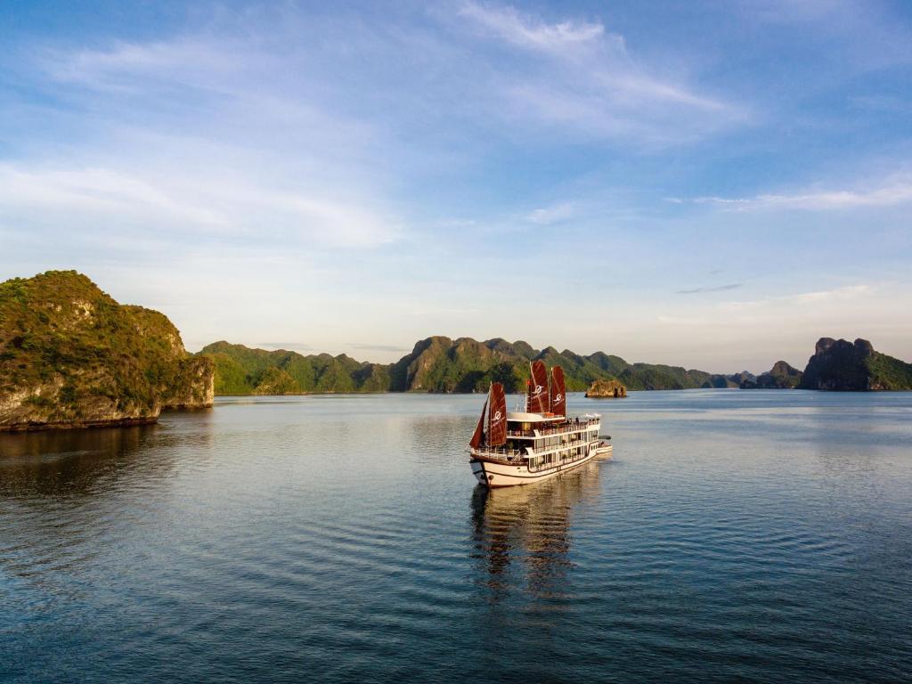 a boat on the water with mountains in the background at V'Spirit Cruise in Ha Long