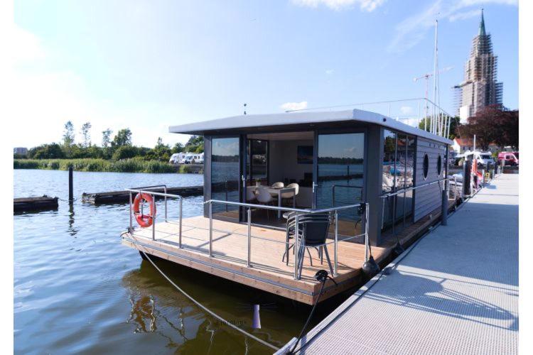 una casa flotante estacionada en un muelle en el agua en Hausboot Fjord Aries mit Dachterrasse in Schleswig, en Schleswig
