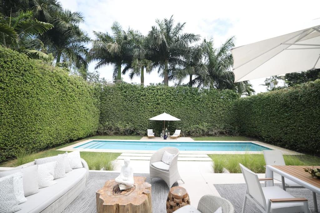 einen Hinterhof mit einem Pool mit weißen Möbeln und einem Tisch in der Unterkunft Villa Naomi - Luxury Design New Home in Miami