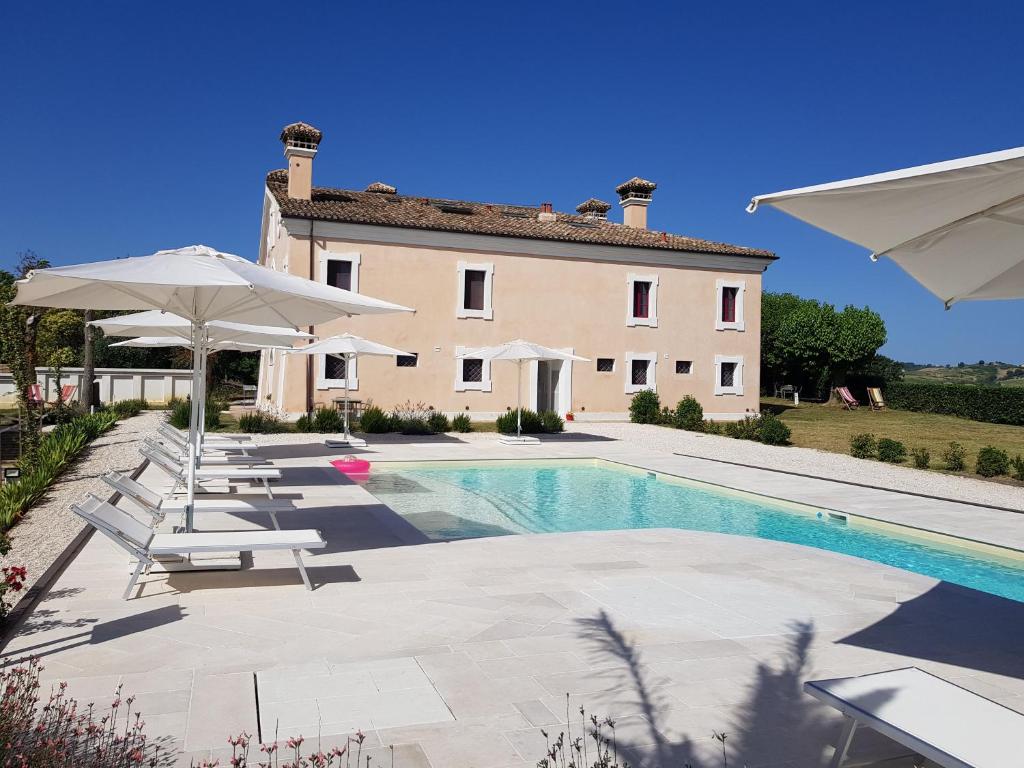 Villa con piscina con sillas y sombrillas. en Villa Montefiore Country Resort en Borghetto