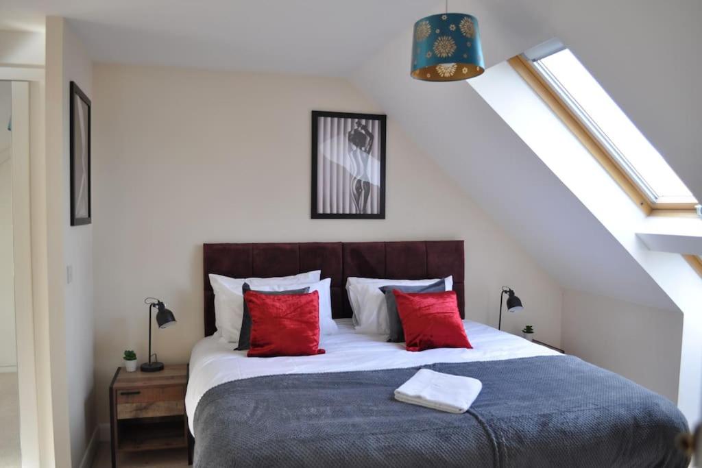 a bedroom with a large bed with red pillows at Beaney View House - Modern, Spacious 4 Bedrooms Ensuites House with Free Wifi and Parkings in Swindon