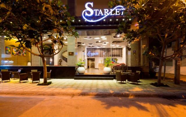un negozio con sedie e tavoli di fronte a un edificio di Starlet Hotel a Nha Trang