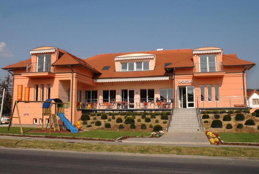 una casa grande con un parque infantil delante de ella en Sportház en Gyenesdiás