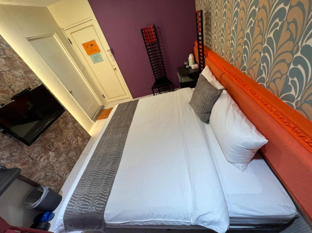 a bed with an orange headboard in a room at Boston Hotel in Chiayi City