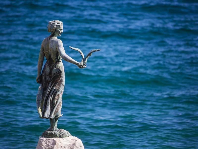 Apartment Marina في أوباتيا: تمثال لامرأة تمسك عصفور فوق الماء