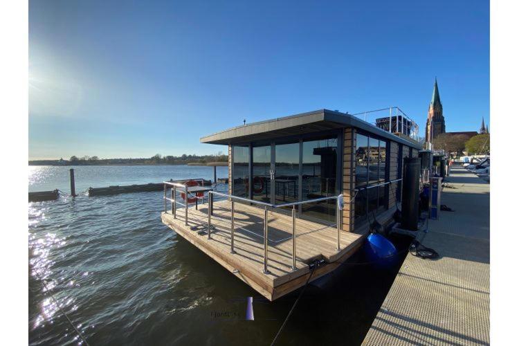 a small boat parked at a dock on the water at Hausboot Fjord Ankerplatz mit Biosauna in Schleswig in Schleswig